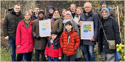 Im Wurzgarten, der sich in unmittelbarer Nähe zur barocken Jesuitenkirche befindet, fand in diesem Jahr die Verleihung des Westenergie Klimaschutzpreises statt. Mit dabei (v. l.): Fabian Wälter (Westenergie), Anne Happe („Büren ist bunt“), Carolin Schepers (Zweckverband „Bevorzugtes Erholungsgebiet Bad Wünnenberg/Büren“), Bürgermeister Burkhard Schwuchow, Imran Ahmed, Irene Blumenthal-Ahmed und Büsra Hancilar zusammen mit ihren Kindern Samih und Siam (alle „Büren ist bunt“). Außerdem (v. l.:): Sabrina Nsanzabandi, die ihren Mann Fiacre Nsanzabandi, einen der aktivsten Gärtner im Wurzgarten, vertritt, Anja Schwamborn (Jugendpflege Büren), Sascha Glaser (Klimaschutzmanager, Stadt Büren), Leah Grewe (Jugendpflege Büren), Peter Abels, Mevlüt Öskul und Hülya Kostuc (alle „Büren ist bunt“). Es fehlt: Jürgen Thiel (Dorfrat Ahden).   Foto: Stadt Büren